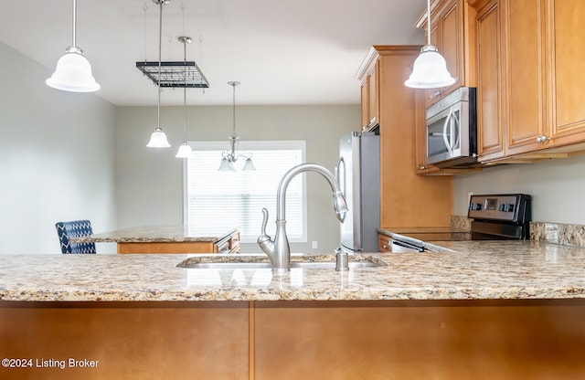 kitchen with hanging light fixtures, light stone countertops, sink, and appliances with stainless steel finishes