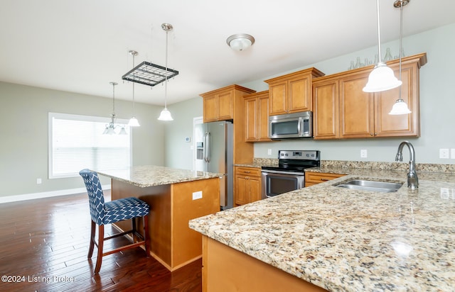 kitchen with stainless steel appliances, a kitchen bar, pendant lighting, sink, and dark wood-type flooring