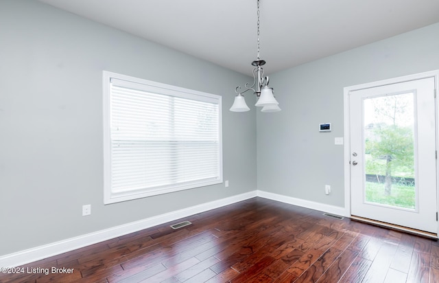 unfurnished dining area with dark hardwood / wood-style floors and an inviting chandelier