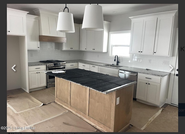 kitchen featuring light stone counters, stainless steel appliances, a sink, white cabinetry, and hanging light fixtures