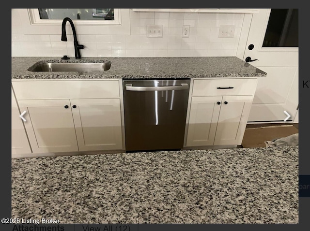 kitchen featuring stainless steel dishwasher, stone countertops, a sink, and white cabinets