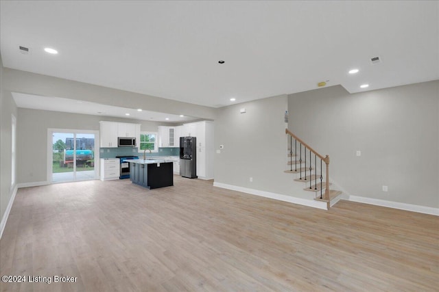 unfurnished living room with sink and light hardwood / wood-style flooring