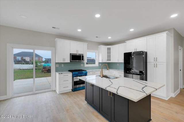 kitchen with a kitchen island with sink, plenty of natural light, sink, and stainless steel appliances