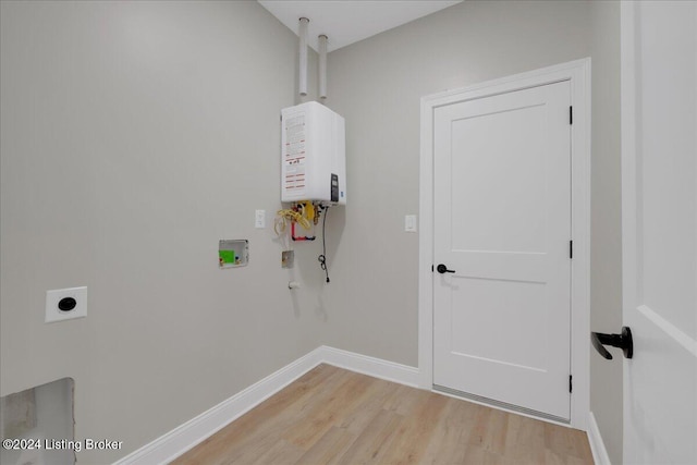 laundry area featuring water heater, hookup for a washing machine, light hardwood / wood-style flooring, and electric dryer hookup