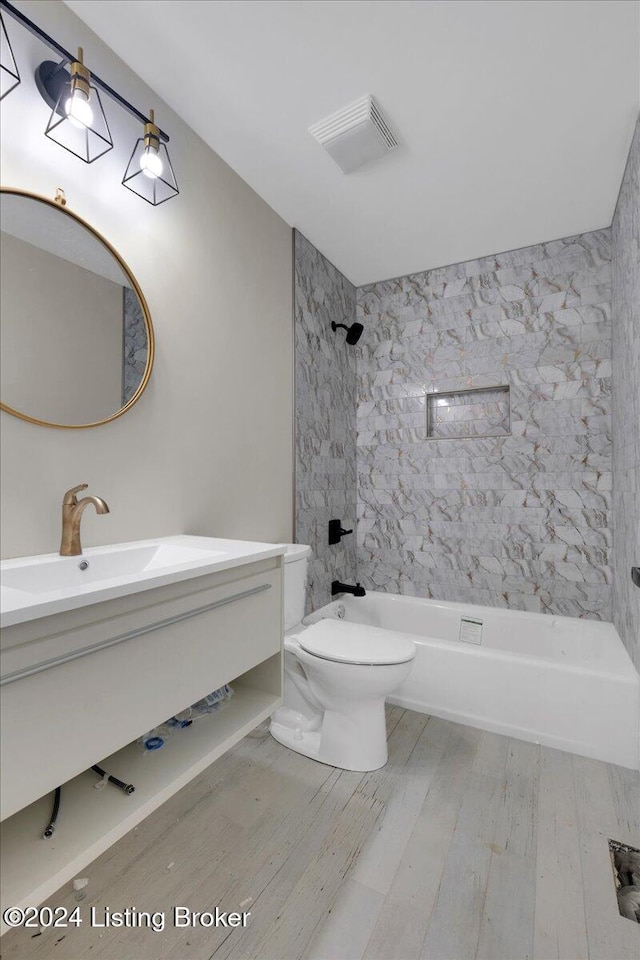 full bathroom with wood-type flooring, vanity, toilet, and tiled shower / bath combo