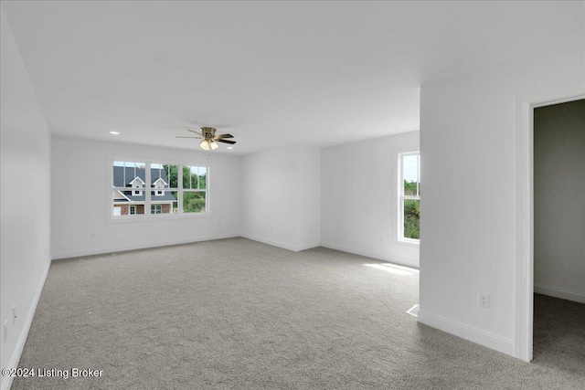 spare room with light colored carpet, ceiling fan, and plenty of natural light