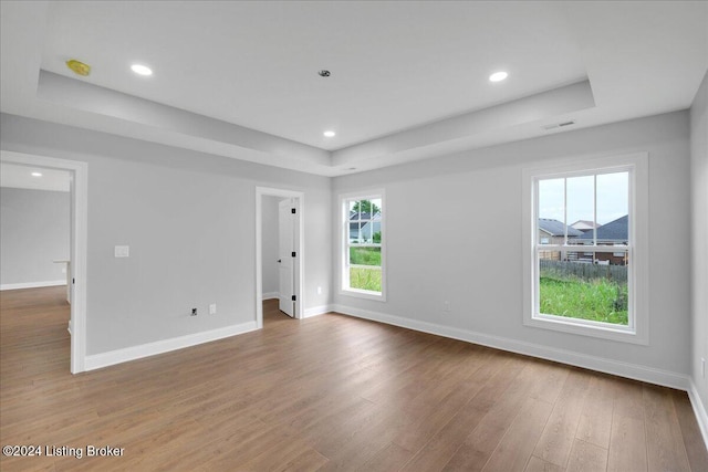 spare room with a tray ceiling and hardwood / wood-style floors