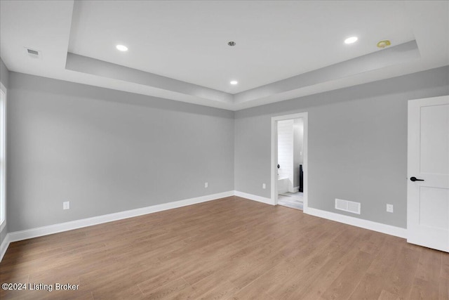 unfurnished room featuring light hardwood / wood-style flooring and a raised ceiling