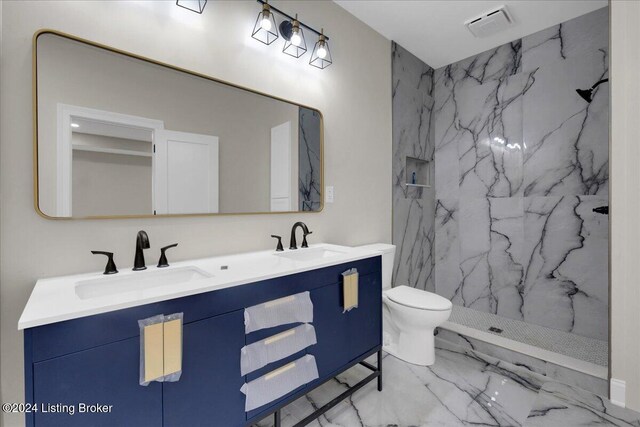 bathroom featuring toilet, vanity, and tiled shower