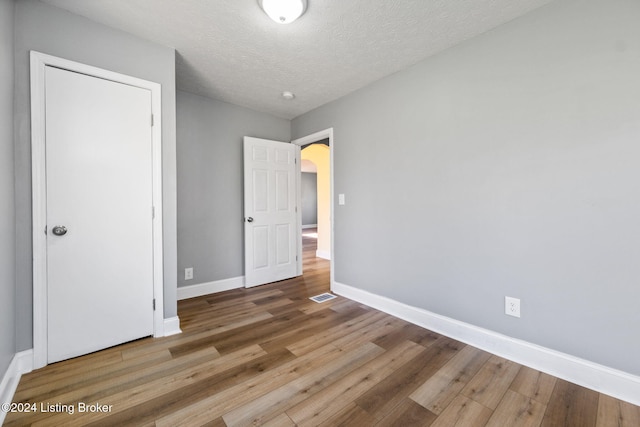 unfurnished bedroom featuring hardwood / wood-style flooring and a textured ceiling