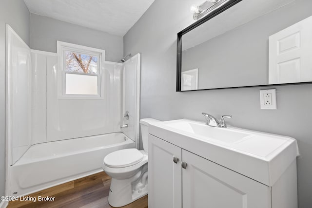 full bathroom featuring a textured ceiling, hardwood / wood-style floors, vanity, bathtub / shower combination, and toilet