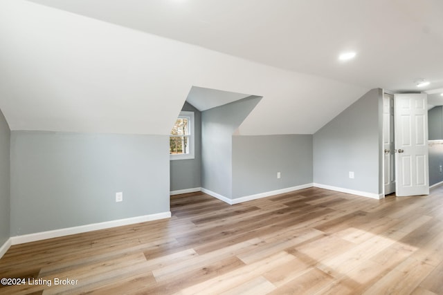 additional living space featuring light wood-type flooring and lofted ceiling