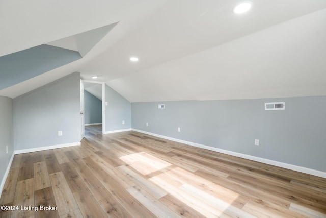 additional living space with light hardwood / wood-style floors and vaulted ceiling