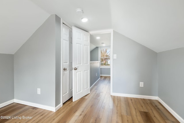 additional living space featuring light wood-type flooring and lofted ceiling