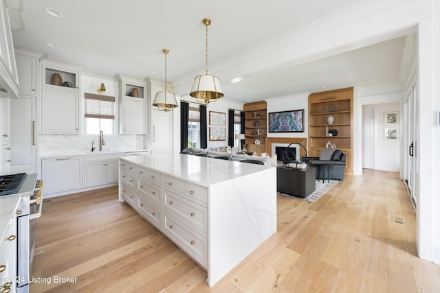 kitchen with a kitchen island, white cabinetry, hanging light fixtures, and light wood-type flooring