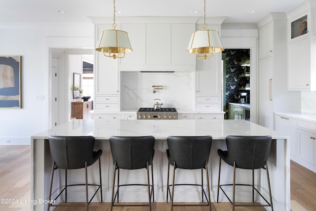 kitchen with a kitchen island, white cabinetry, light stone countertops, decorative backsplash, and light hardwood / wood-style floors