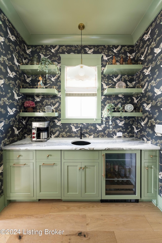 bar with decorative light fixtures, beverage cooler, sink, and green cabinets