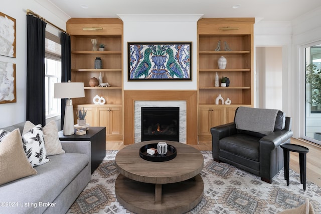 living room with a premium fireplace, light hardwood / wood-style flooring, a healthy amount of sunlight, and crown molding