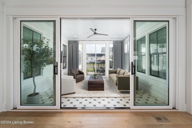 doorway featuring ornamental molding, hardwood / wood-style flooring, and ceiling fan