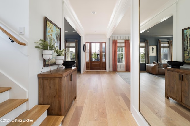 entryway with light wood-type flooring and crown molding