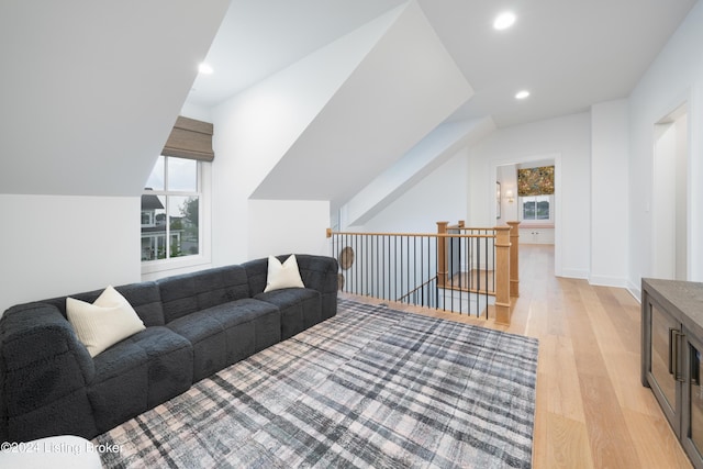 living room featuring lofted ceiling, a healthy amount of sunlight, and light hardwood / wood-style floors