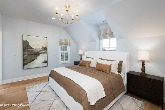 bedroom with light hardwood / wood-style floors, a notable chandelier, multiple windows, and vaulted ceiling