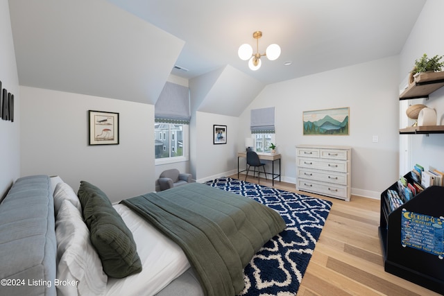 bedroom with an inviting chandelier, vaulted ceiling, and light hardwood / wood-style flooring