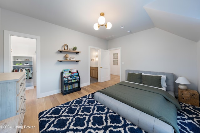 bedroom with lofted ceiling, a notable chandelier, ensuite bathroom, a closet, and light hardwood / wood-style flooring