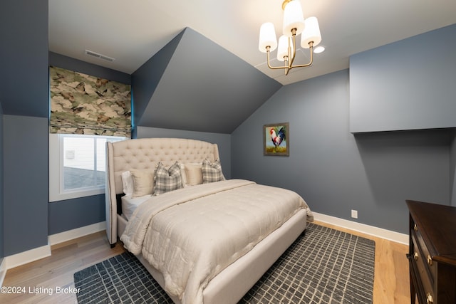 bedroom featuring light hardwood / wood-style flooring, vaulted ceiling, and an inviting chandelier