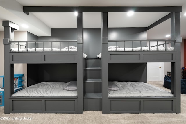 bedroom featuring beamed ceiling and light colored carpet