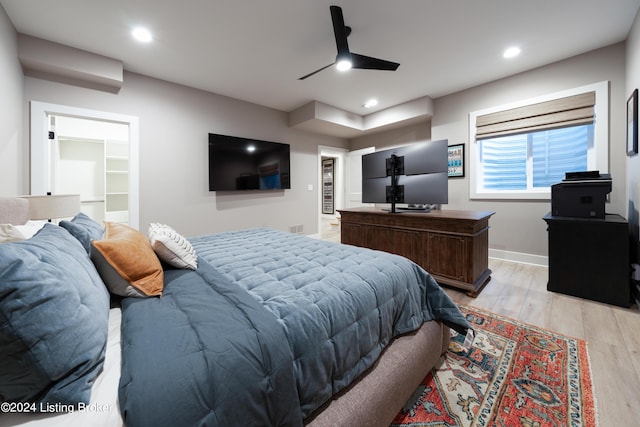 bedroom with a closet, light wood-type flooring, a spacious closet, and ceiling fan