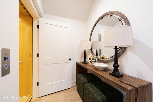 hallway featuring light wood-type flooring and vaulted ceiling