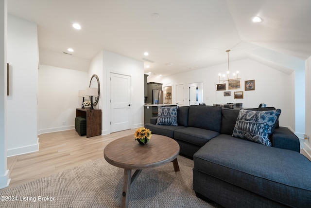 living room featuring lofted ceiling, an inviting chandelier, and light hardwood / wood-style floors