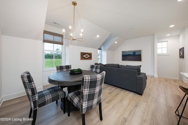 dining area with light hardwood / wood-style floors, plenty of natural light, an inviting chandelier, and vaulted ceiling