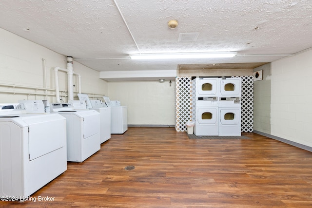 laundry room featuring dark wood-type flooring, stacked washer and clothes dryer, independent washer and dryer, and a textured ceiling