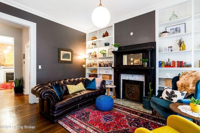 living room featuring built in shelves, hardwood / wood-style flooring, and crown molding