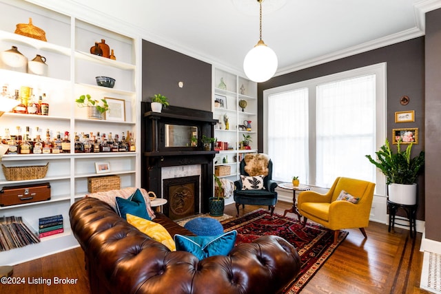 living room with ornamental molding, hardwood / wood-style floors, built in features, and a premium fireplace