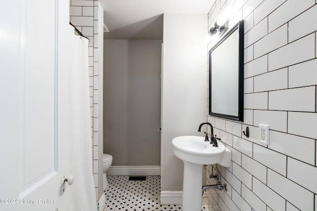 bathroom with toilet, tile walls, and walk in shower