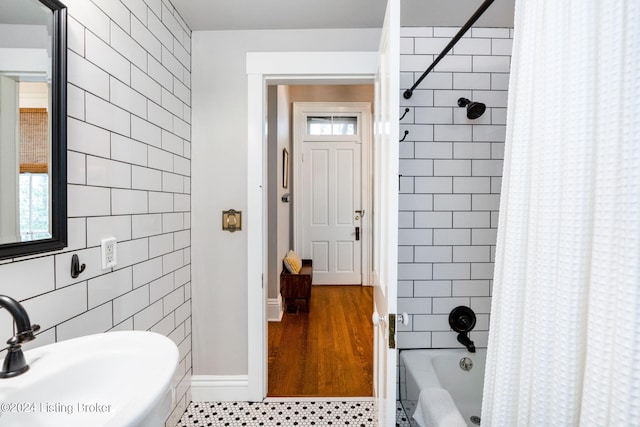 bathroom with hardwood / wood-style floors, sink, shower / bath combination with curtain, and tile walls