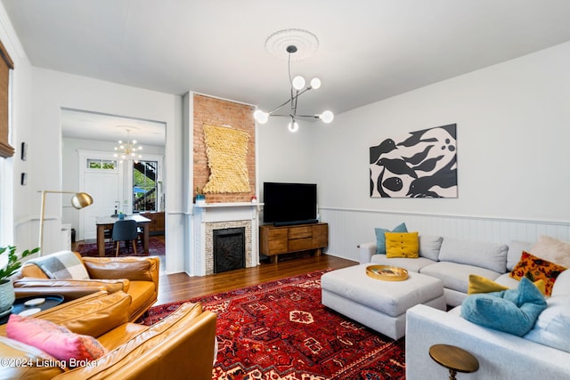 living room with a large fireplace, dark hardwood / wood-style flooring, and an inviting chandelier