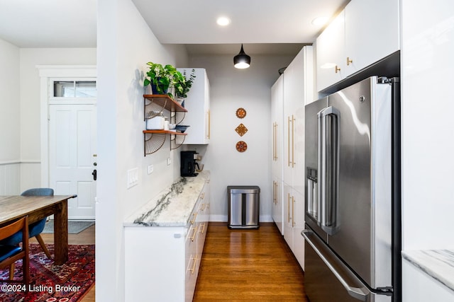 kitchen with dark wood-type flooring, white cabinetry, high end refrigerator, and light stone counters