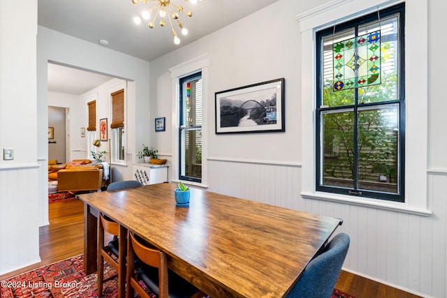 dining space with a chandelier, wood-type flooring, and a healthy amount of sunlight