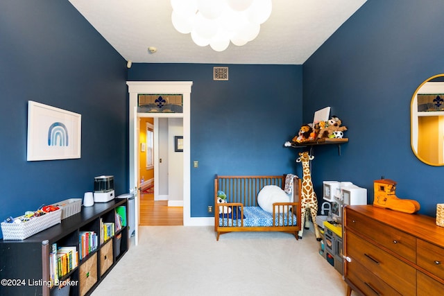 bedroom featuring a nursery area and carpet floors