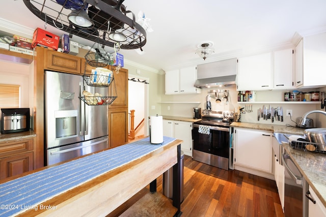 kitchen with stainless steel appliances, dark hardwood / wood-style flooring, white cabinets, crown molding, and wall chimney range hood