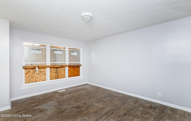 empty room featuring dark hardwood / wood-style flooring and a textured ceiling