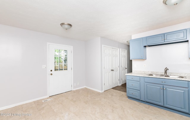 kitchen with blue cabinets, sink, and a textured ceiling