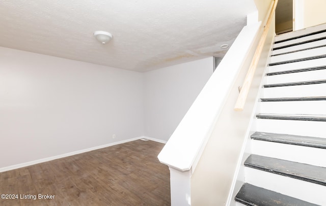 stairs with wood-type flooring and a textured ceiling