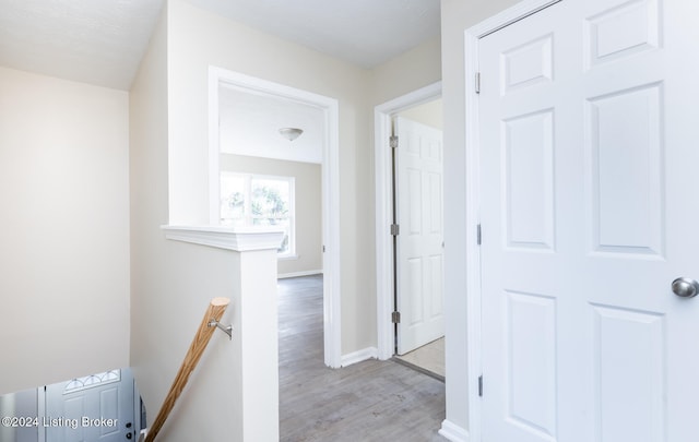 hall with a textured ceiling and light hardwood / wood-style flooring