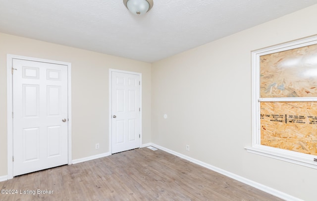 unfurnished bedroom featuring a textured ceiling and light hardwood / wood-style flooring