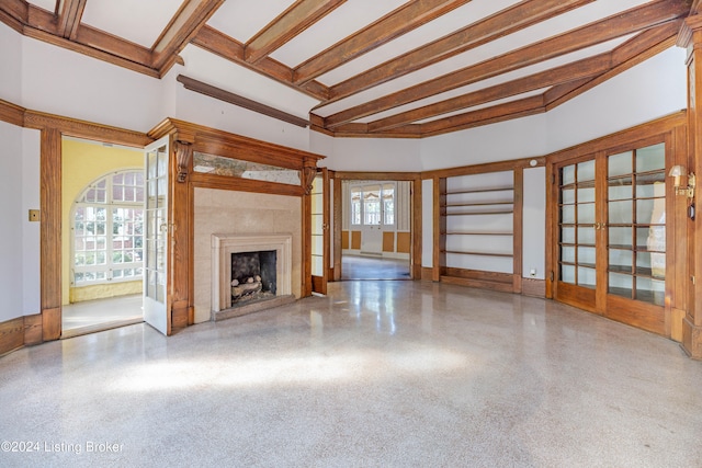 unfurnished living room with beamed ceiling, a healthy amount of sunlight, and french doors